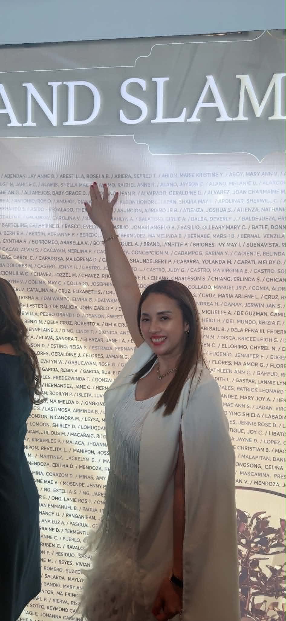 Ruth Abestilla beside the Sun Life Grand Slam recognition wall of advisor names