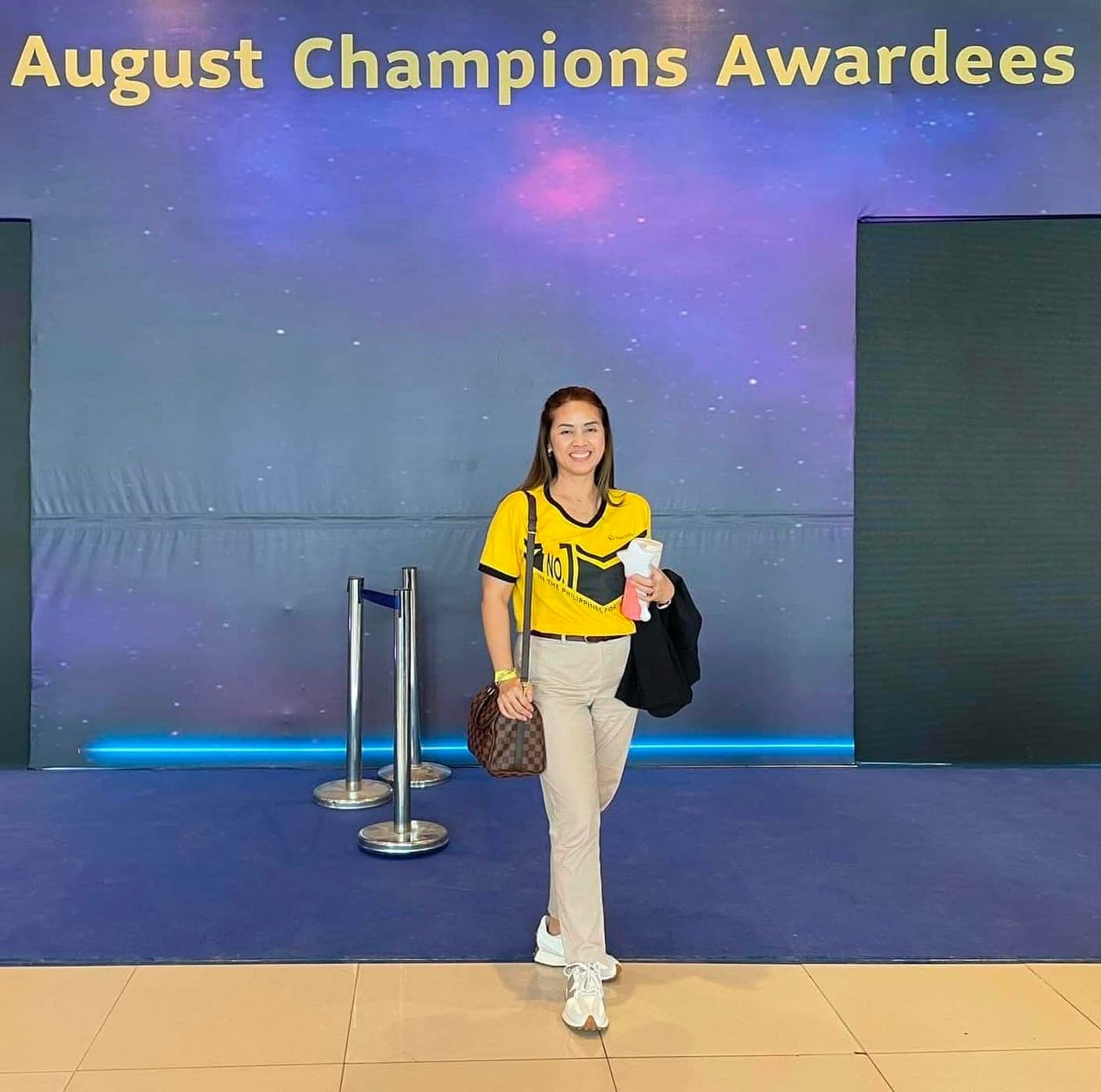 Ruth Abestilla in front of the Sun Life August Champions Awardees stage