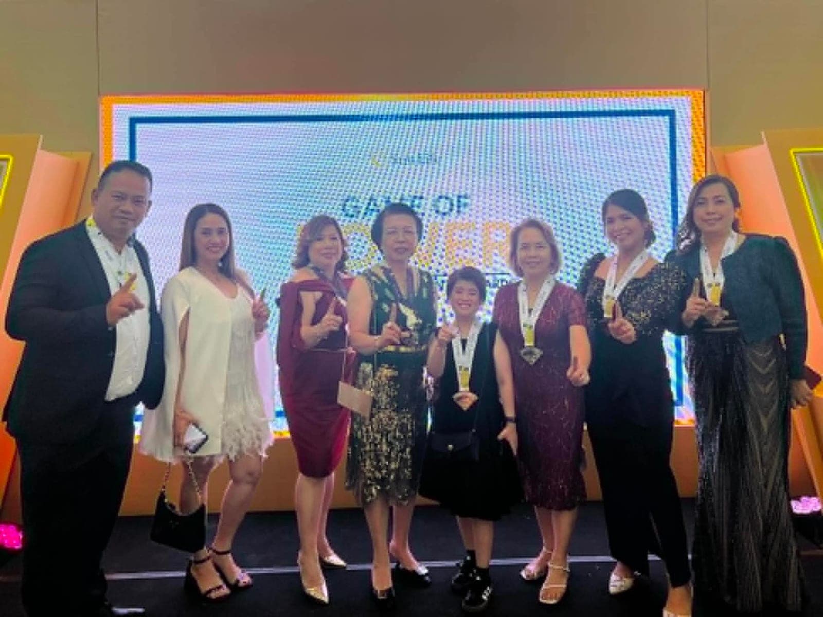 Ruth Abestilla with her agency team receiving a group recognition on stage