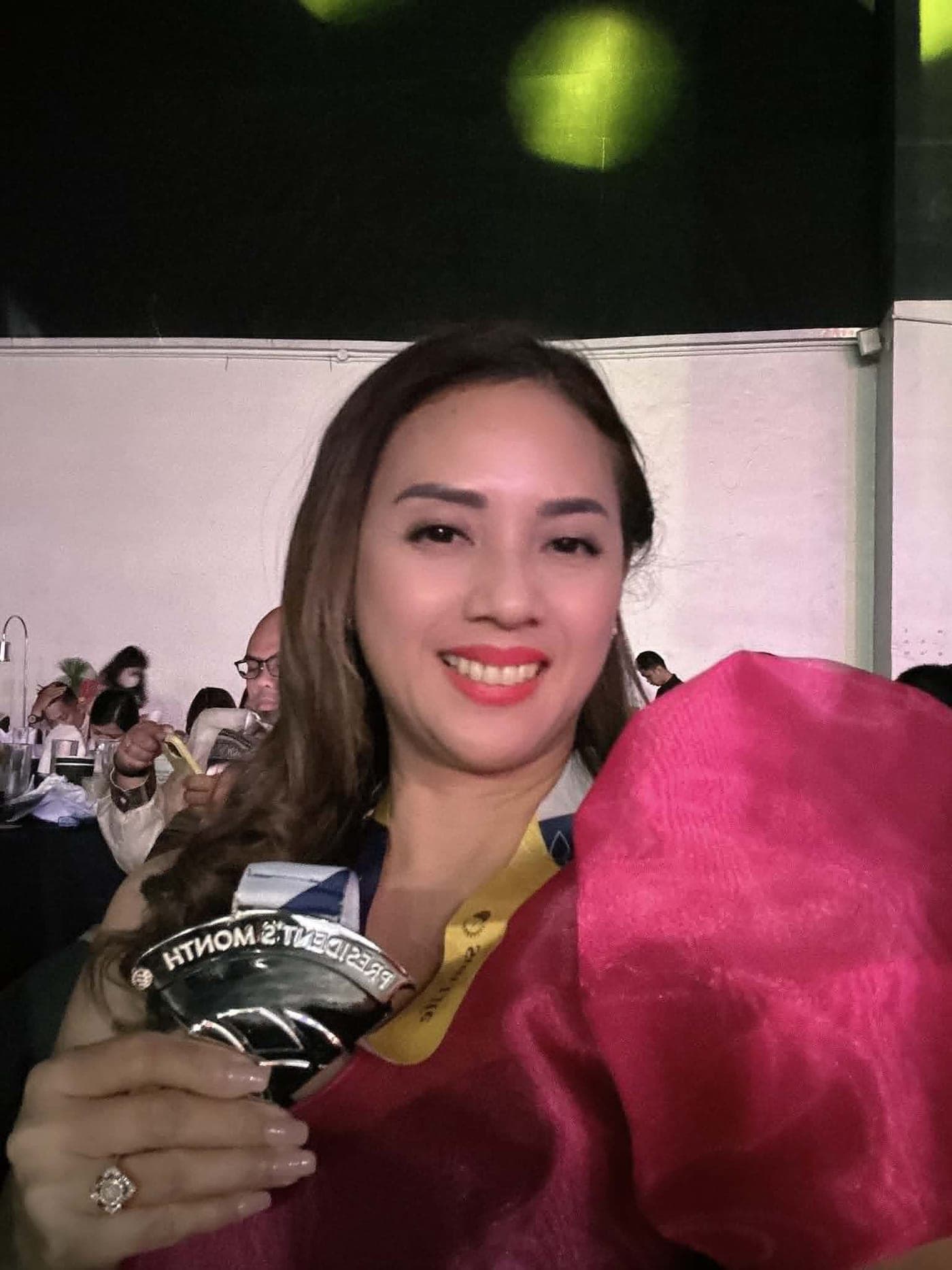 Ruth Abestilla holding a President's Club recognition medal at a Sun Life awards night